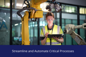 Factory worker in a high‑visibility vest using a tablet to operate an industrial robotic arm inside a modern manufacturing facility.