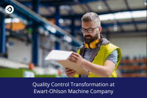 Person in a high‑visibility vest reviewing a clipboard in a large industrial facility, representing quality control transformation at Ewart‑Ohlson Machine Company.
