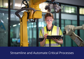 Factory worker in a high‑visibility vest using a tablet to operate an industrial robotic arm inside a modern manufacturing facility.