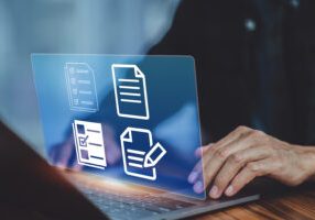 A man engaged with his laptop, surrounded by document icons on the screen, symbolizing productivity and digital organization.