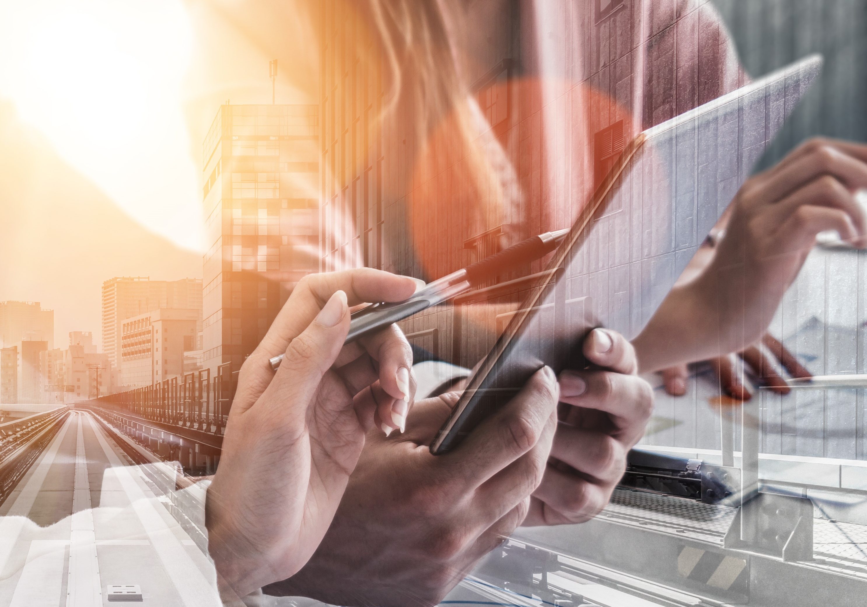 A group of business individuals engaged with a tablet, set against a backdrop of a bustling city skyline.
