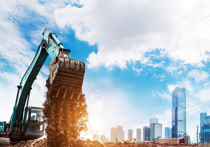 Excavator in action with city in the background.